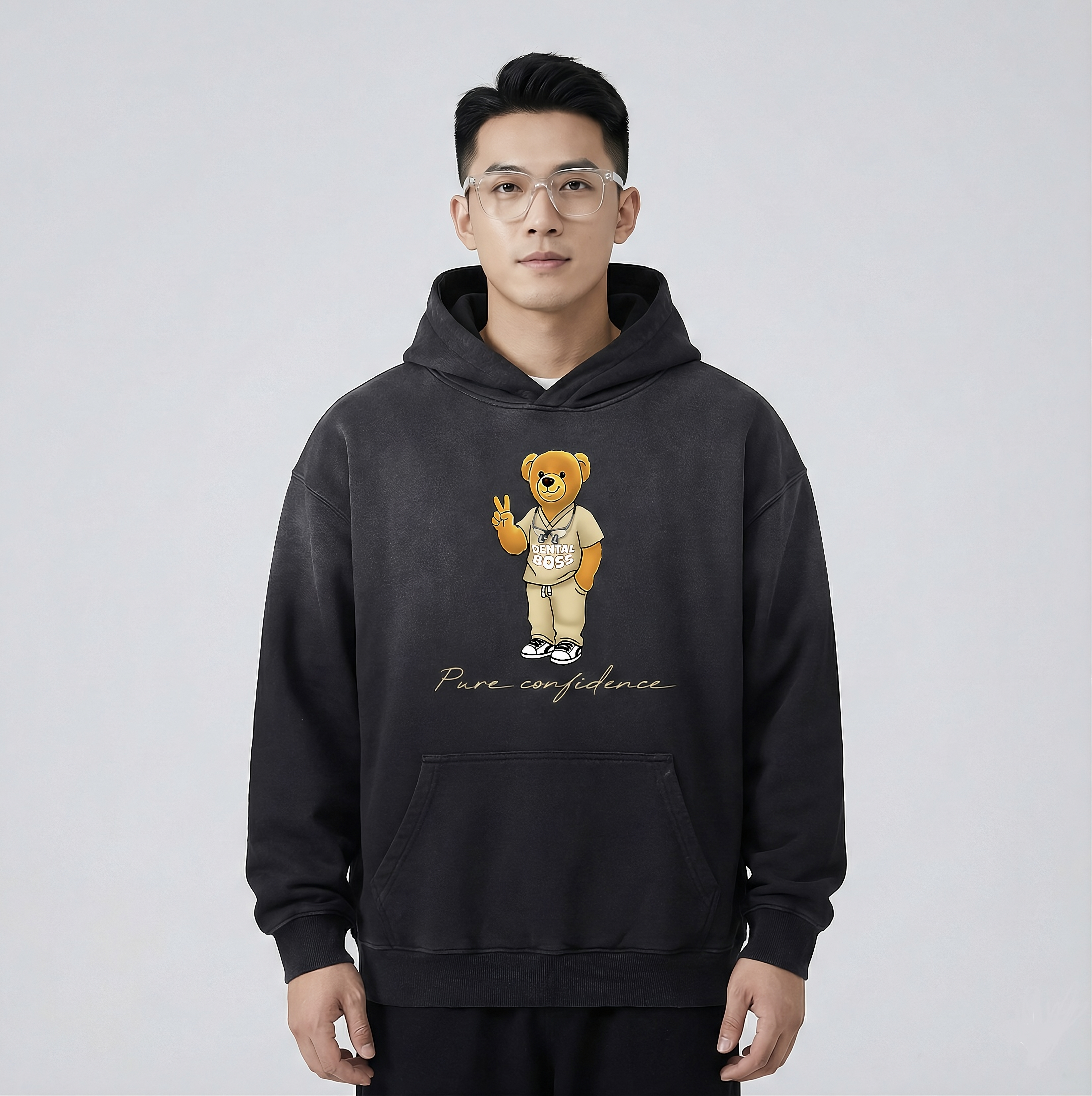 Person wearing a black hoodie with a teddy bear graphic and 'Pure confidence' text on a light gray background